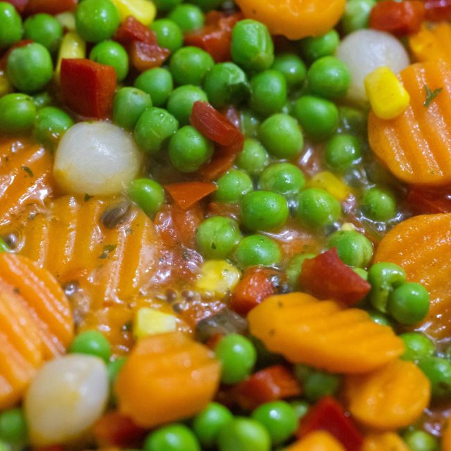 Vibrant close-up of mixed vegetables including carrots and peas in a stew.