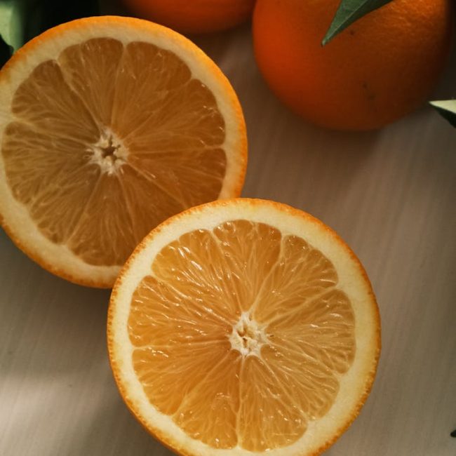 Close-up view of fresh oranges with sliced halves, showcasing vibrant citrus textures.